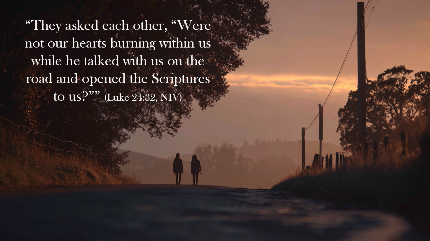 Two people walk together down a quiet rural road at dusk, silhouetted against a fading sky with trees and fence lines along the way, evoking companionship and shared journey, overlaid with Luke 24:32 about hearts burning as Jesus opens the Scriptures.